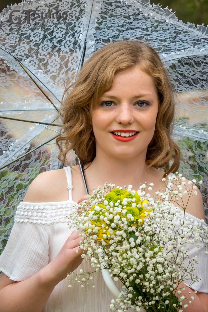 Mikayla with a white lace parasol and a bunch of fresh flowers