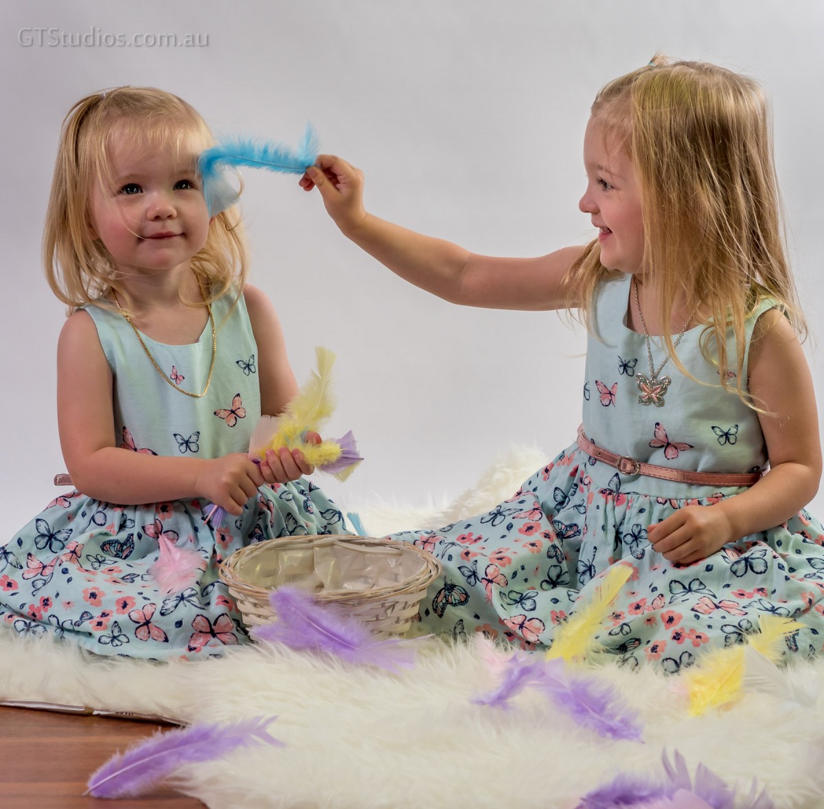 Tickled - beautiful young girls with feathers on rug